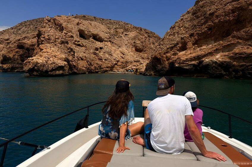 A boat with three people on a rocky coastline. 3