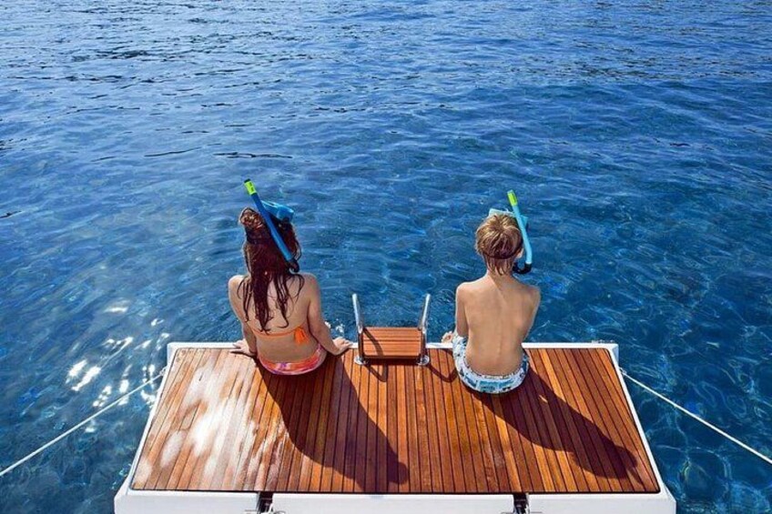 Two people on a wooden boat in clear blue water. 5