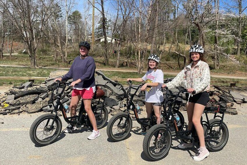 Three people on bicycles in a park with trees and a paved path. 4