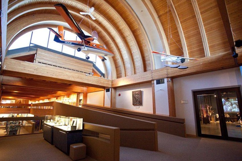 A spacious interior with a high arched wooden ceiling, a display of model airplanes, and a seating area. 5