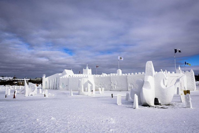 A snow-covered castle with flags, a large ice sculpture of a horse, and a snowy landscape. 2