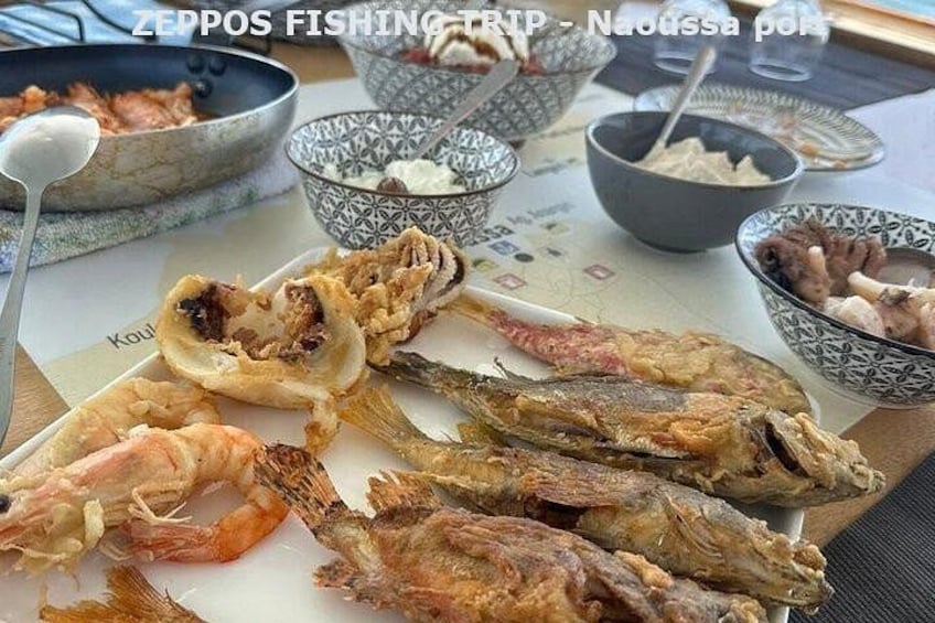 Verschiedene Meeresfrüchte, darunter frittierter Fisch, Garnelen und Calamari, serviert auf einem Tisch mit Schälchen für Dipsaucen. 5