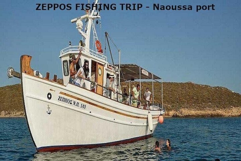Ein Boot namens ZEPPOS N.P. 143 im Hafen von Naoussa mit Personen an Bord und Wasser drumherum. 1