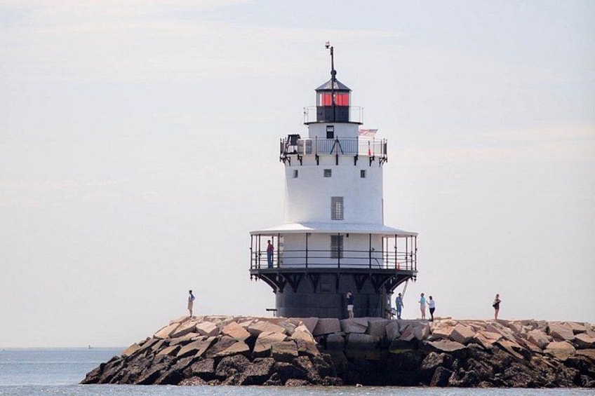 A lighthouse on a rocky outcrop with people standing on it. 2