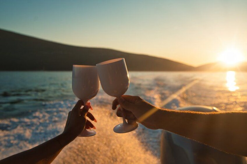 Deux personnes trinquent avec des verres de vin, le soleil se couche sur une étendue d’eau. 5