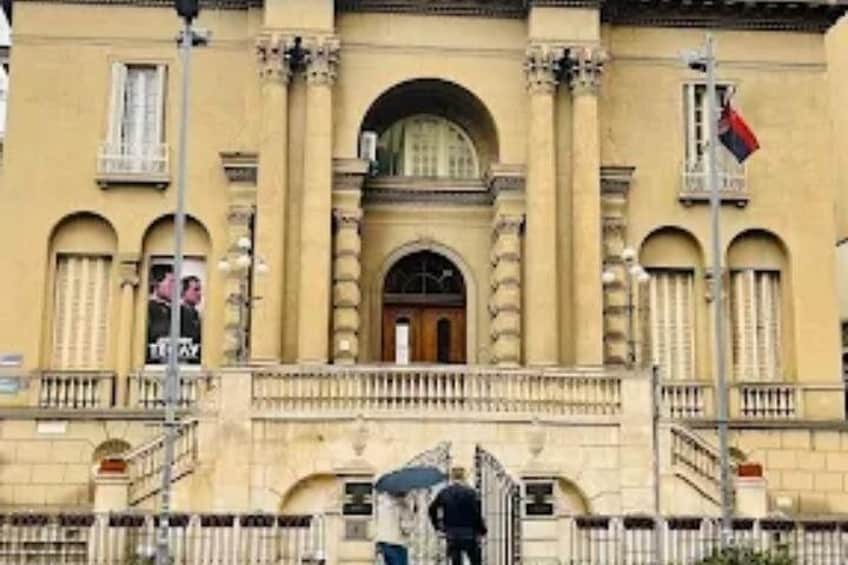 Un edificio clásico con columnas, una entrada central y una bandera. 3