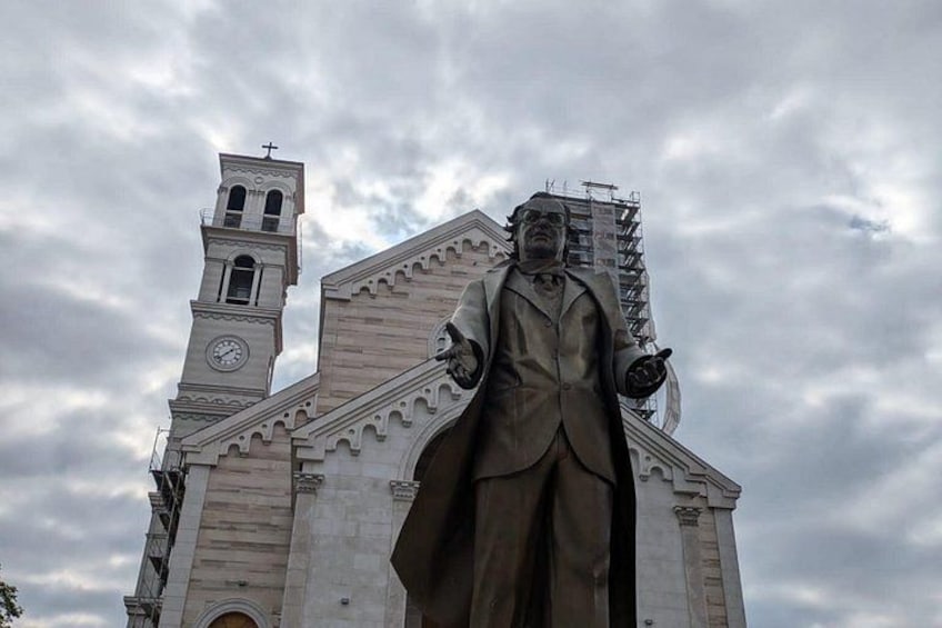Un'imponente statua di fronte a una chiesa con una torre dell'orologio. 2