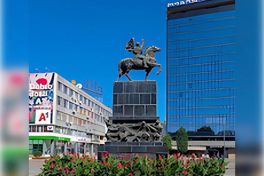 Una statua raffigura un cavallo e un cavaliere, un edificio con facciata blu e un cartello con la lettera 'A'. 3
