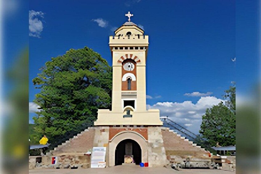 Un campanario con una cruz en la parte superior, rodeado de árboles y un cielo despejado. 1