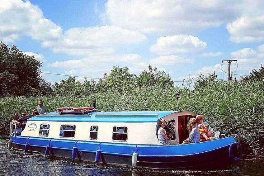 Un barco fluvial estrecho navegando por un río rodeado de vegetación. 2