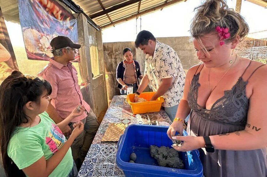 A group of people at a food stall with a table, a blue container, and a person serving food. 2