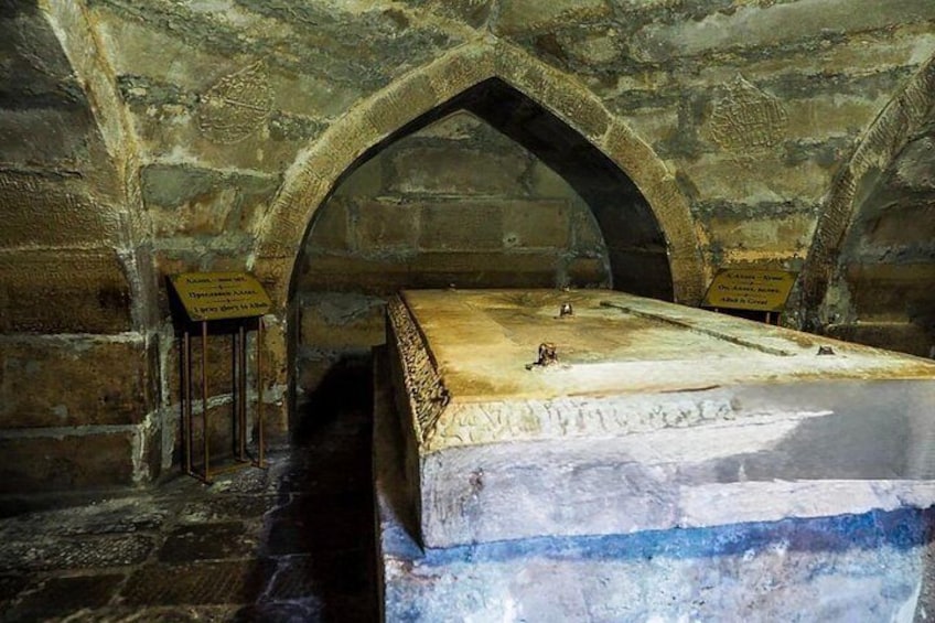 An ancient stone structure with arched ceilings and a central stone platform. 3
