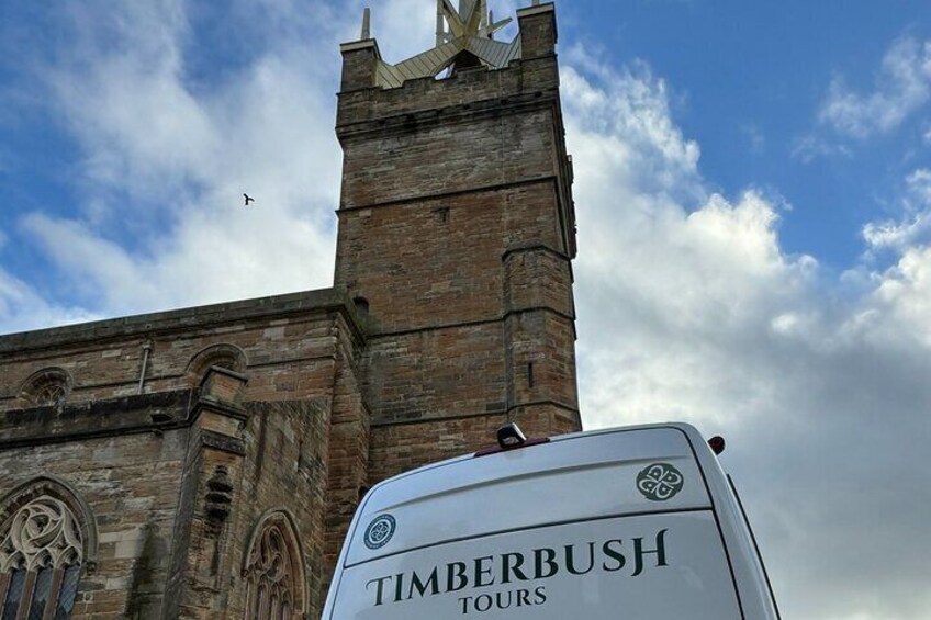 Un edificio storico con una torre dell'orologio e un cartello con la scritta Timberbush Tours. 4