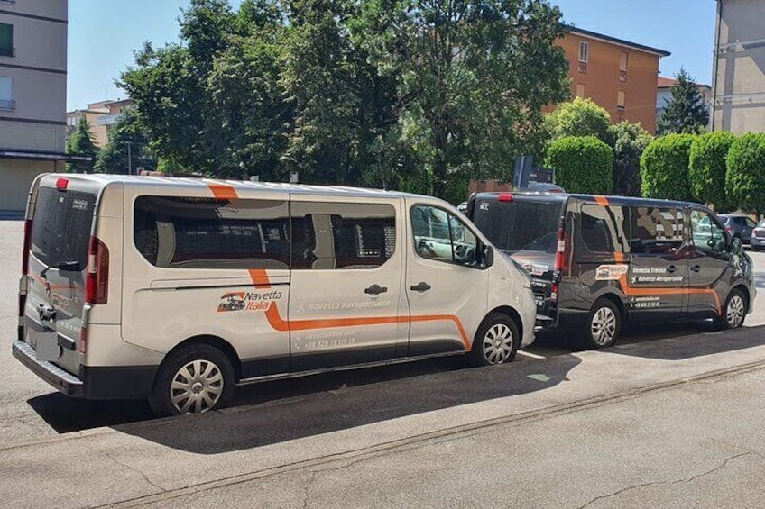 Een witte bus met oranje strepen geparkeerd op een stadsweg. 4