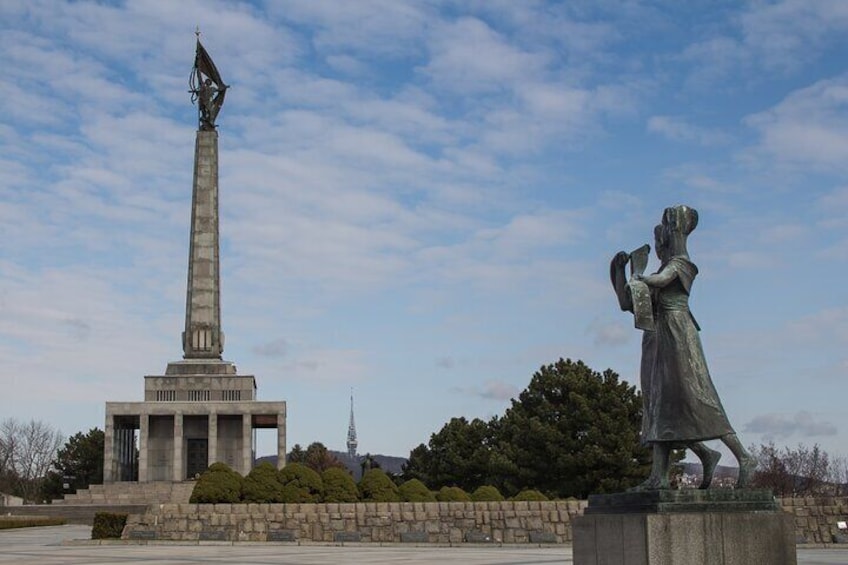 Een monument met een hoge obelisk en een standbeeld van een vrouw die een boek vasthoudt. 2