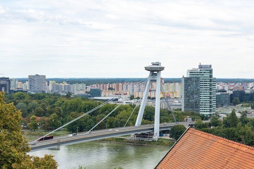 Een kabelbrug met een centrale toren, een rivier en een stadsgezicht met gebouwen op de achtergrond. 3