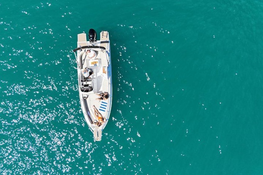 A white motorboat with a cabin and seating area, floating on turquoise water. 4