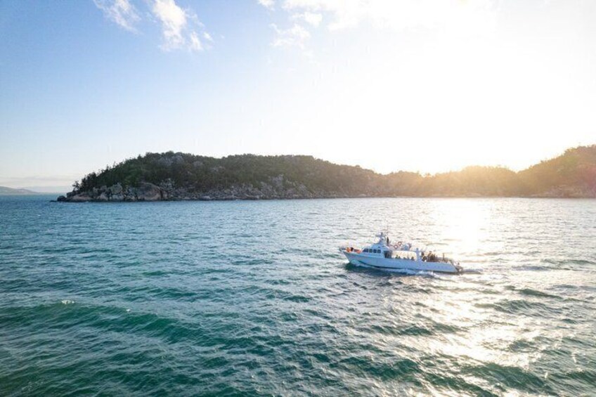 A boat on calm waters with a hilly island in the background. 4
