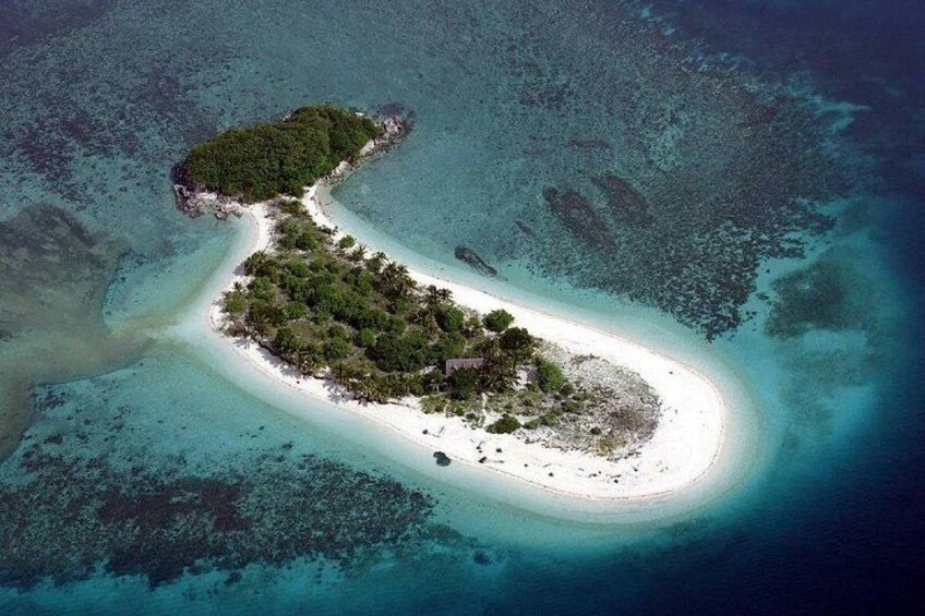 An aerial view of a small island with a white sandy beach and dense green vegetation. 2