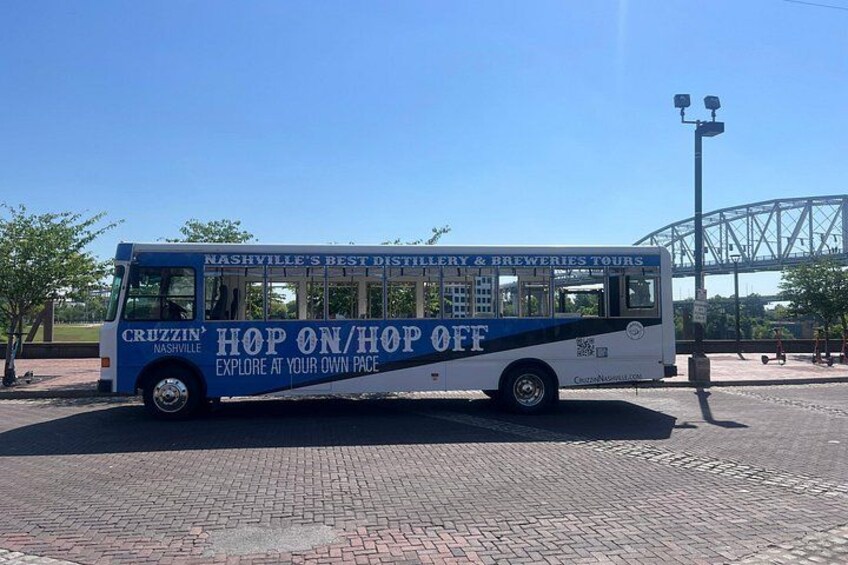 En blå og hvid bus med teksten 'Nashville's Best Distillery & Breweries Tours' og 'Hop On/Hop Off'. 2