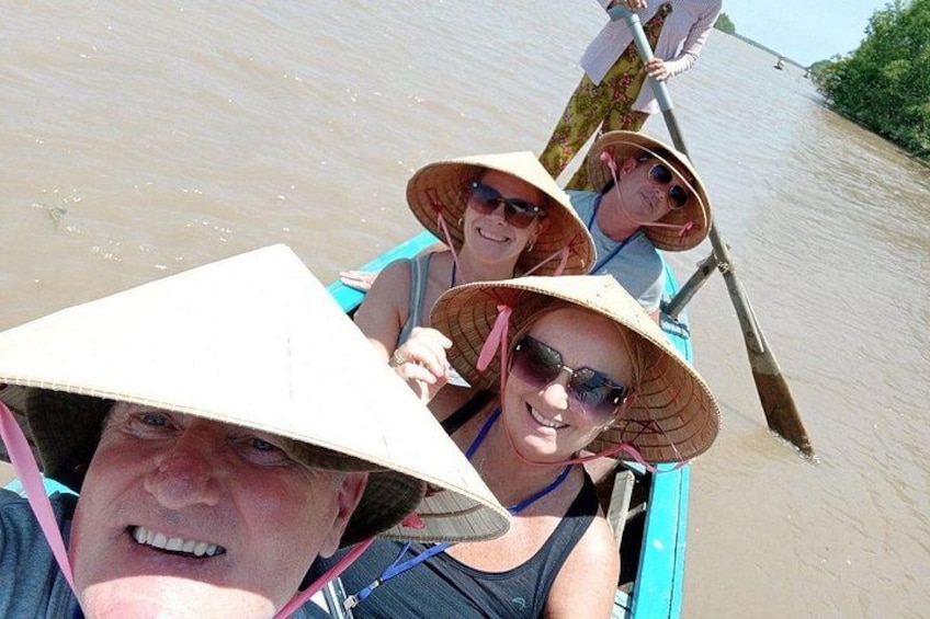 Mensen in een boot met kegelvormige hoeden, peddelend op een rivier. 4