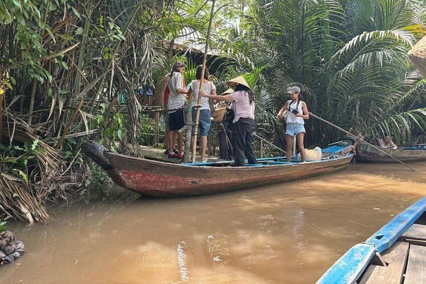 Een groep mensen op een boot in een rivier, omgeven door weelderige begroeiing. 2