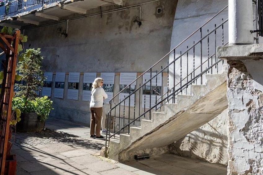 A woman standing on a staircase under a building with posters on the wall. 2