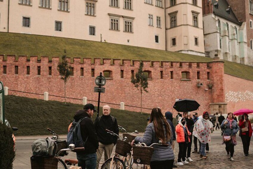 A group of people standing on a cobblestone street with a historic building in the background. 3