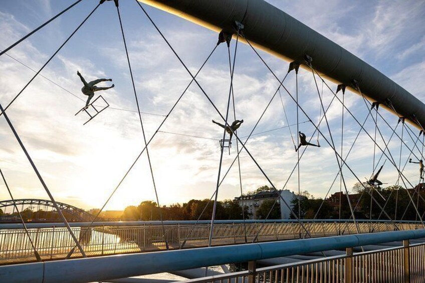 A suspension bridge with cables and a person performing an aerial maneuver. 4