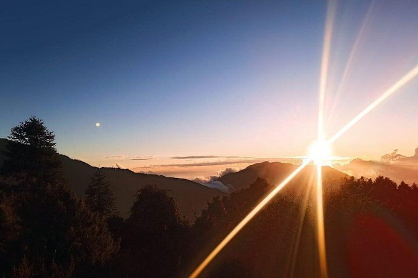 A sunrise over a mountainous landscape with trees silhouetted against the sky. 3