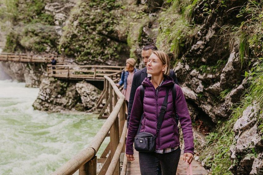 A wooden bridge over a river with rocky cliffs and greenery. 2