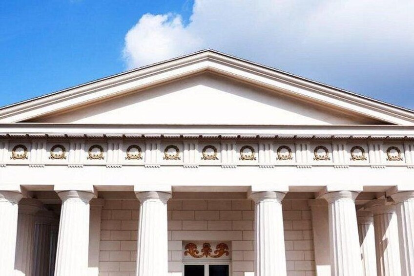 Un bâtiment de style néoclassique, doté d’un fronton triangulaire, de colonnes et de moulures décoratives. 4
