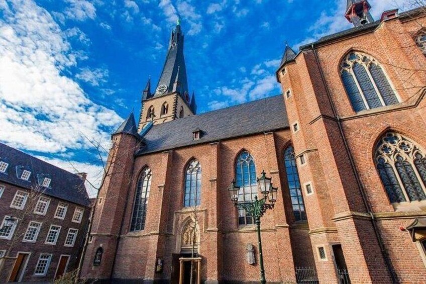 Une église en briques rouges, dotée d’un clocher élevé et de fenêtres en arc de cercle. 2