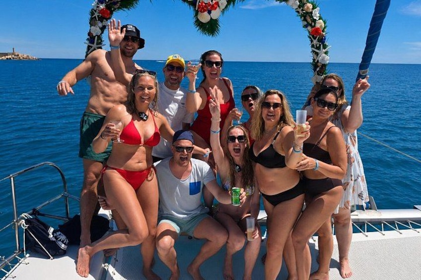 A group of people on a boat with a decorative arch and the sea in the background. 2