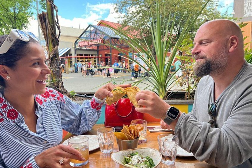 Twee personen dineren buiten, met een tafel, stoelen en een glas drinken. 1