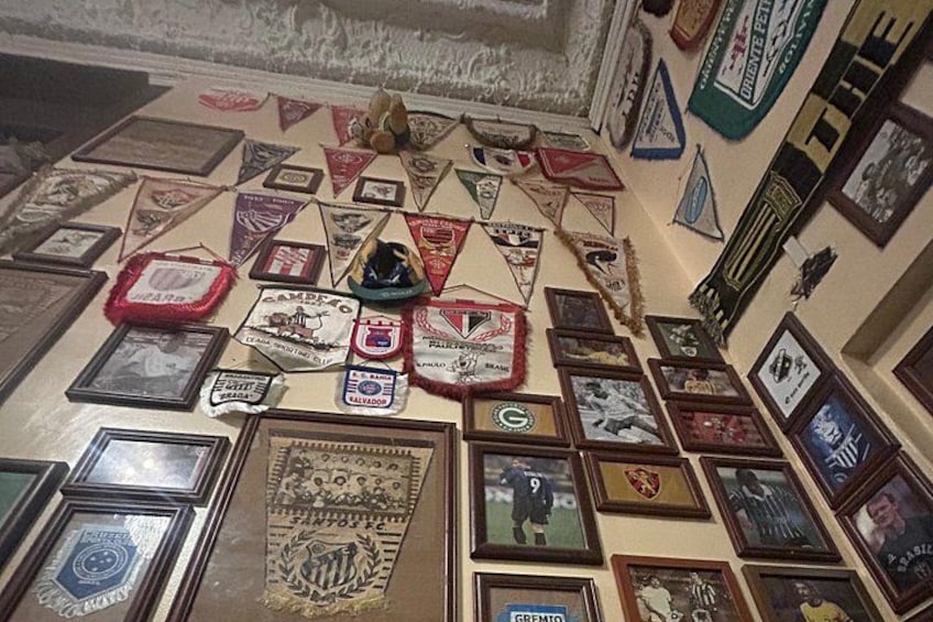 A wall decorated with various framed items, including flags, certificates, and photographs. 5