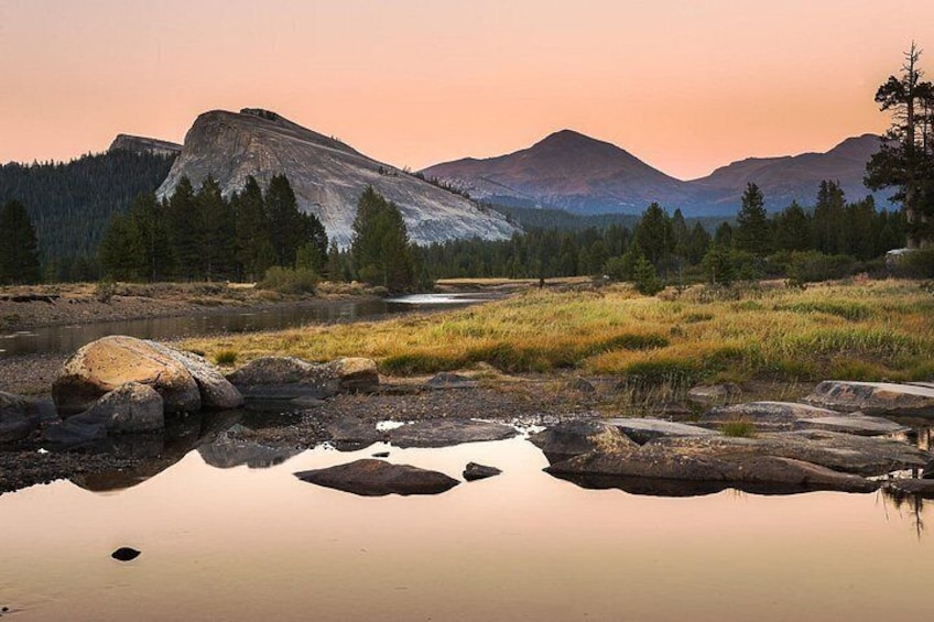 A mountain landscape with a clear sky, a calm river, and a forested area. 4