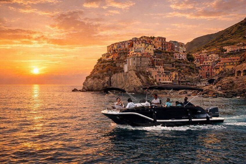 A boat on calm water with a sunset and a coastal village in the background. 4