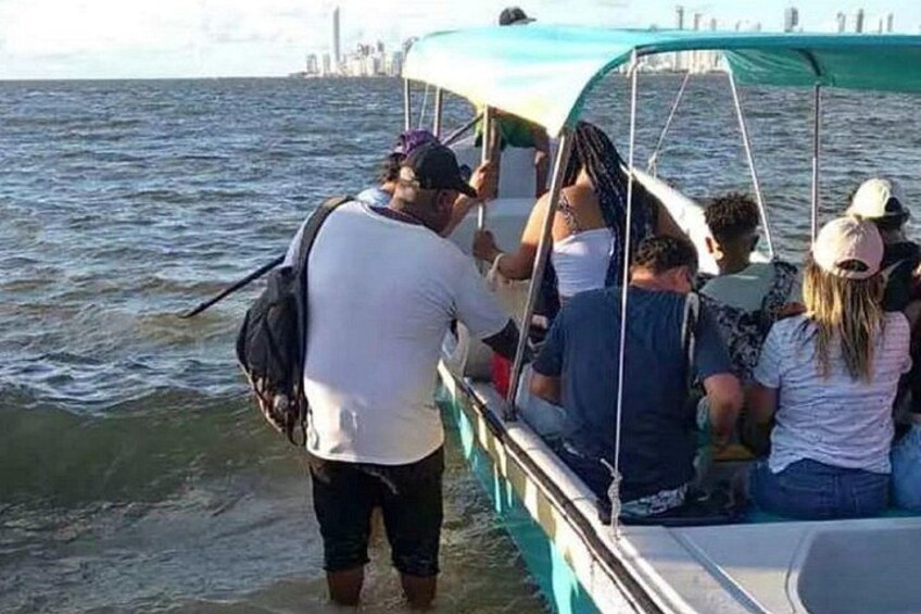A group of people on a boat with a city skyline in the background. 2