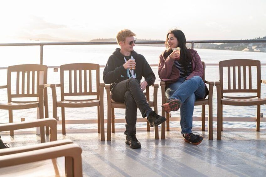 Two people sitting on wooden chairs by a waterfront. 3