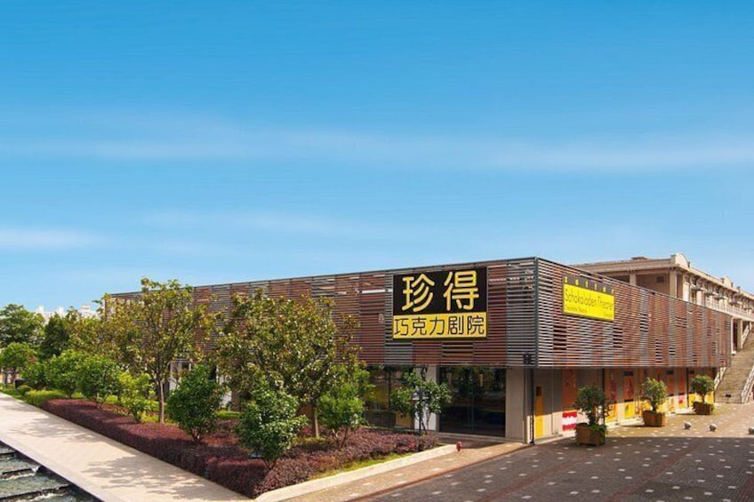 A modern building with a sign that reads 'Xingda' and 'Xingda Power Station.' There are trees and a parking lot in front. 1