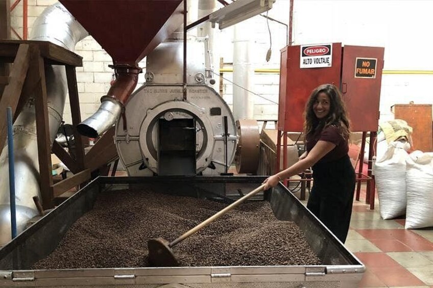 Eine Person bedient eine Kaffeeröstmaschine in einer gewerblichen Umgebung. 2