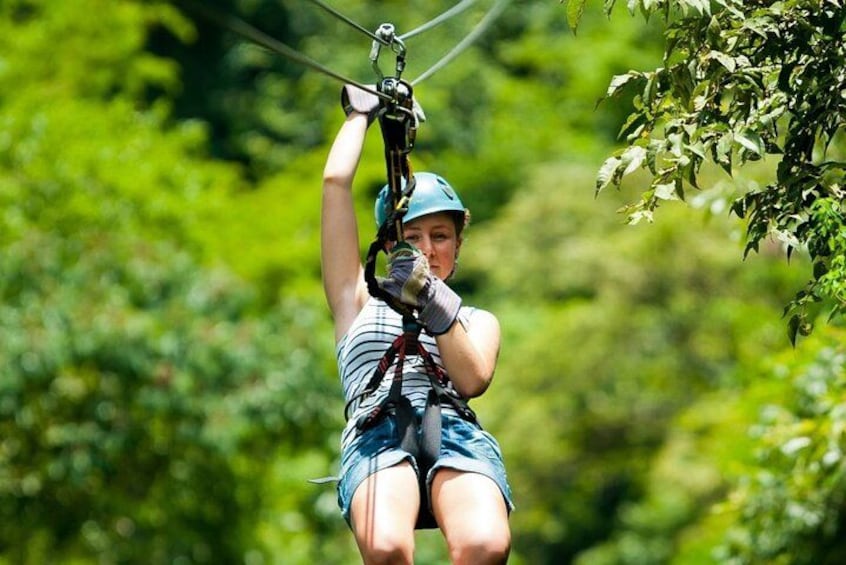 En person suser afsted i et zipline-anlæg gennem et skovområde. 4