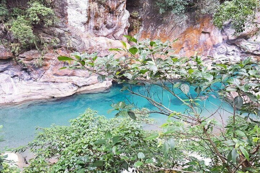 A turquoise pool surrounded by rocky cliffs and lush greenery. 3