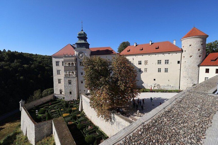 Un castello con una torre dell'orologio, una torre circolare e un giardino curato. 1