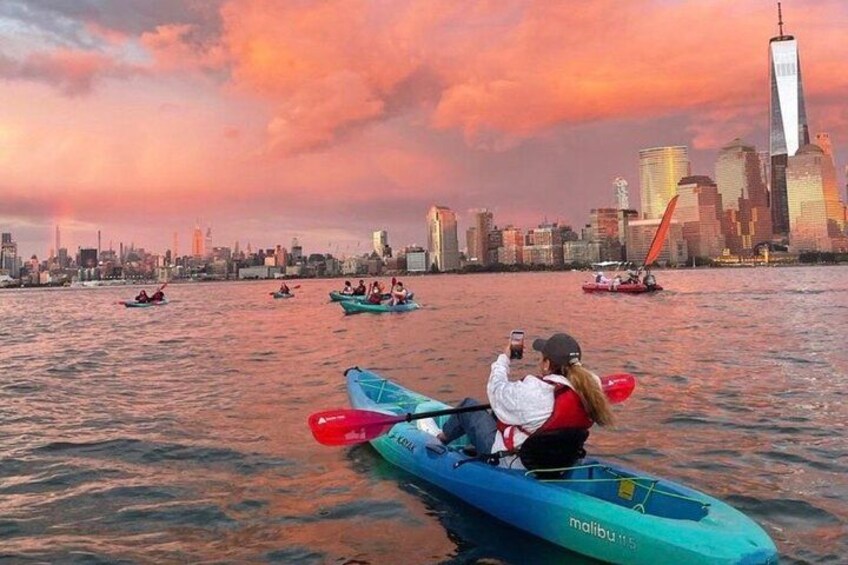 Tramonto su uno skyline cittadino con persone che fanno kayak in acqua. 1