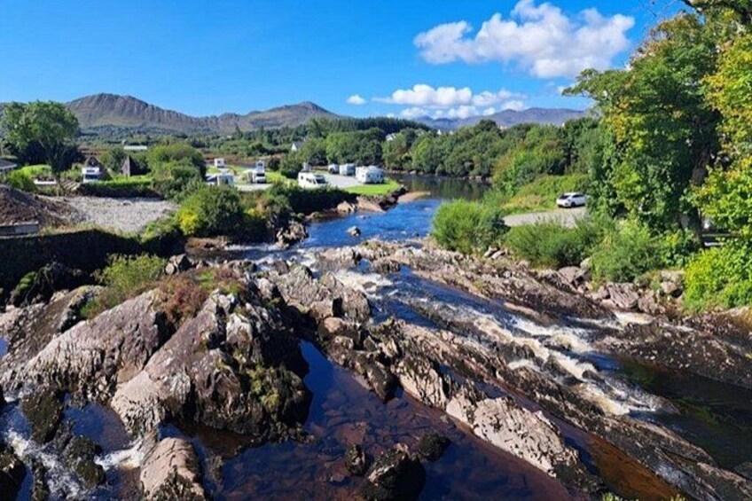 Un río serpentea a través de un paisaje rocoso, con montañas al fondo y un cielo despejado. 3