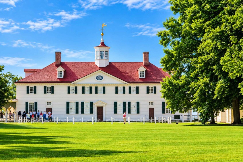 A historic building with a red roof, white walls, and a central tower with a weather vane. 2
