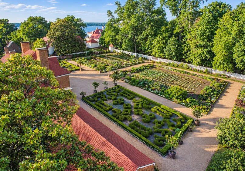 A well-maintained garden with geometric plant arrangements, a brick pathway, and a white fence. 4