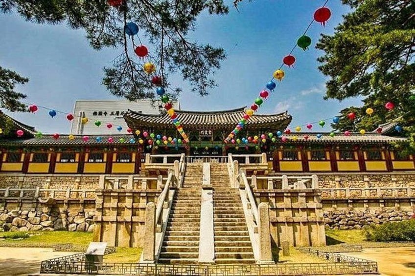 A traditional building with a tiled roof, stone steps leading up to a gate, and colorful decorations. 5